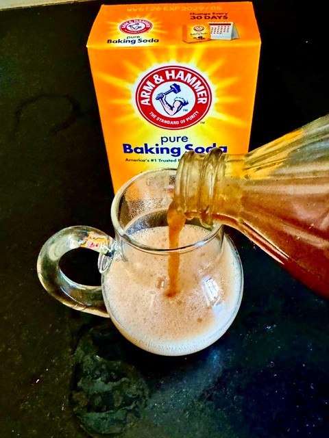 Vinegar and baking soda poured into a glass measuring cup, fizzing on contact