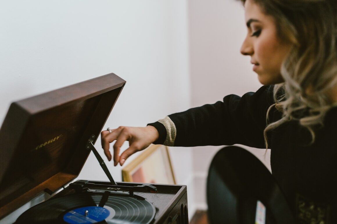 A woman setting a record on a vintage turntable in a warm, lived-in room