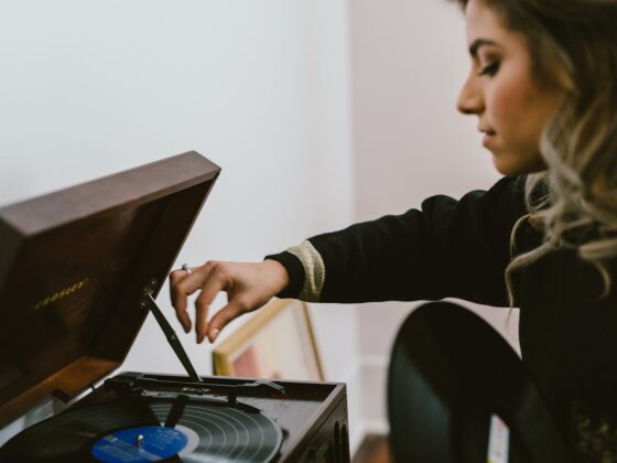 A woman setting a record on a vintage turntable in a warm, lived-in room
