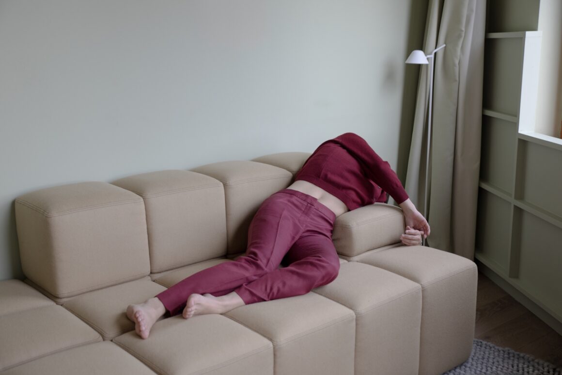 A person collapsed face-down on a beige couch in a calm living room