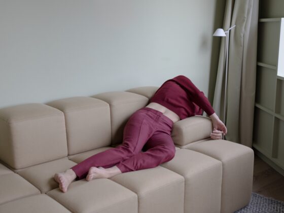 A person collapsed face-down on a beige couch in a calm living room