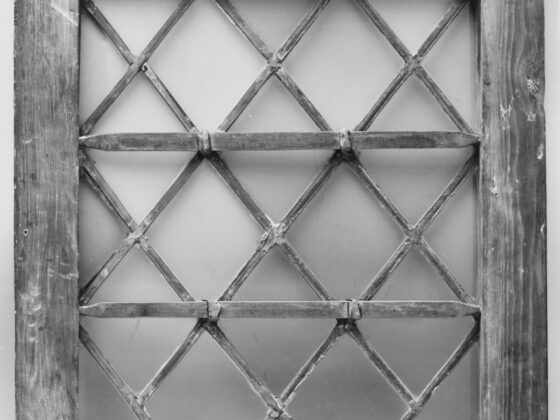 An old diamond-pane leaded window in a weathered wood frame, black and white