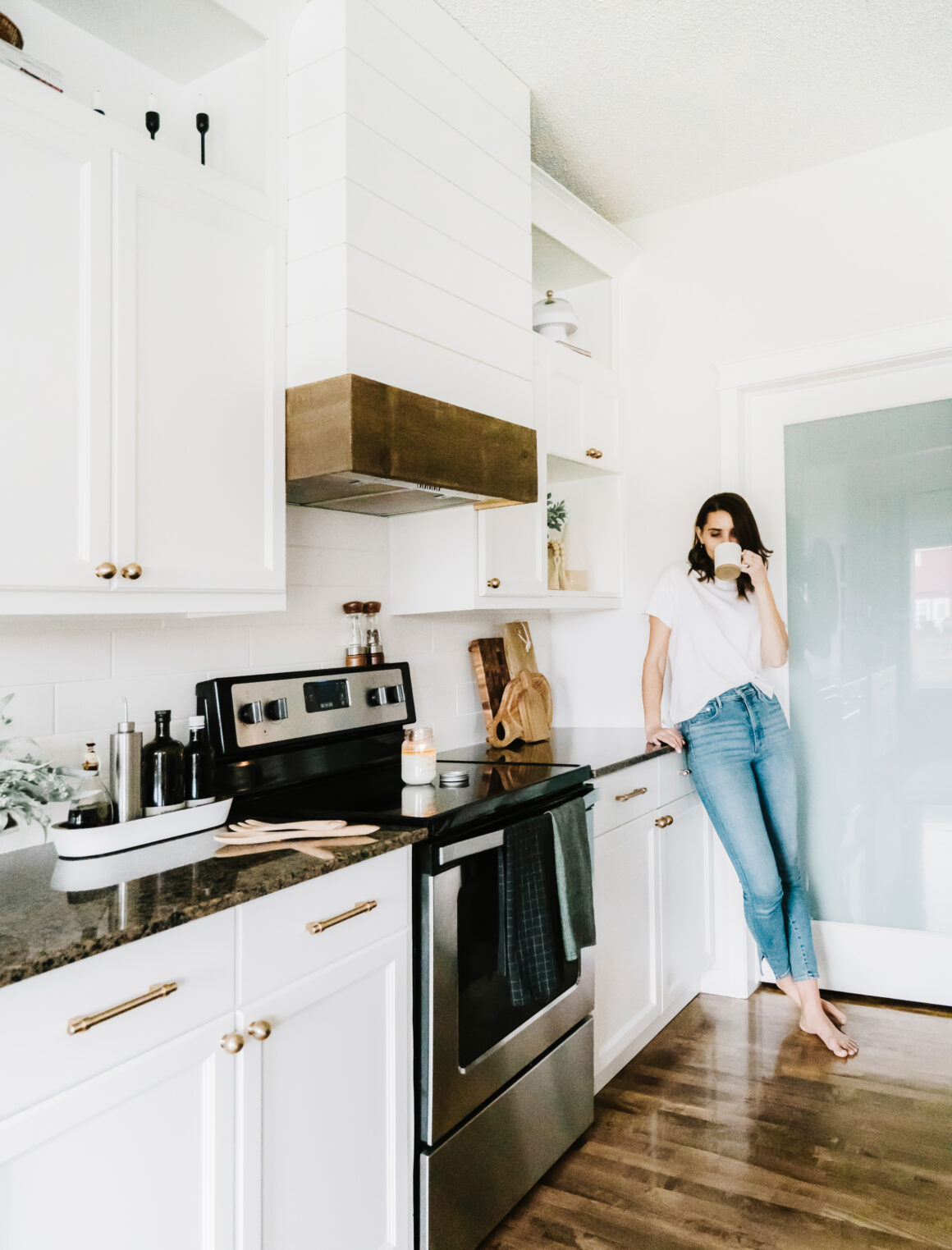 A woman relaxing with coffee in her bright, clean kitchen at home.