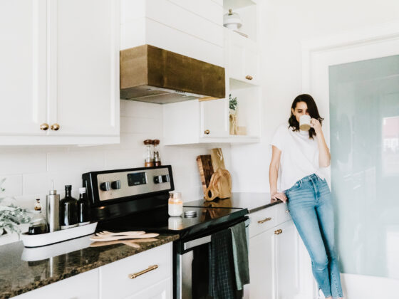 A woman relaxing with coffee in her bright, clean kitchen at home.