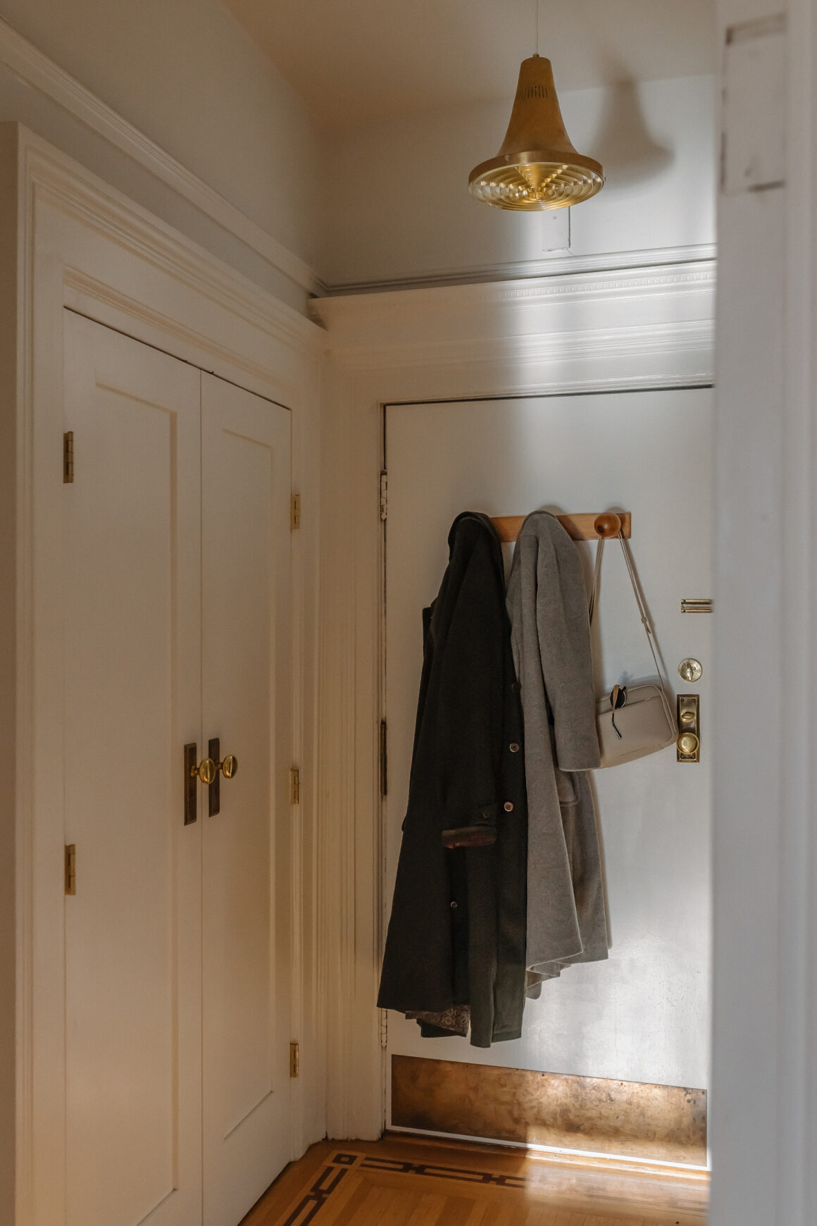 coat and sweater hanging on a hook beside the front door in a small entryway.