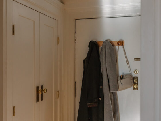 coat and sweater hanging on a hook beside the front door in a small entryway.