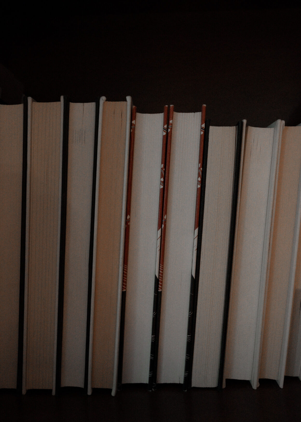 A row of books on a shelf turned backwards, with the page edges facing out