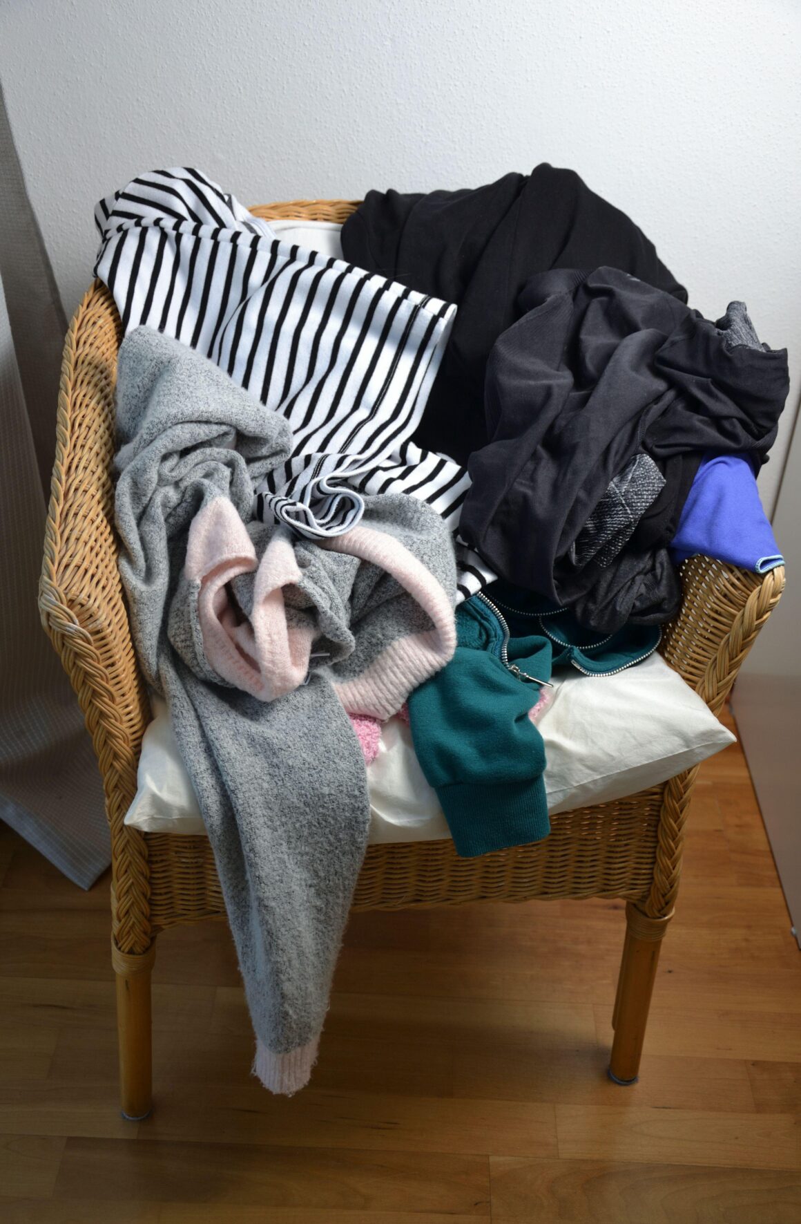A wicker chair piled high with clothes