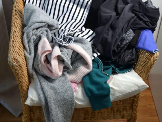 A wicker chair piled high with clothes