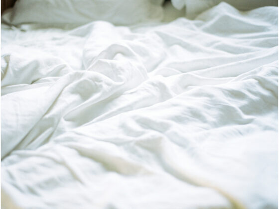 An unmade bed with rumpled white sheets.