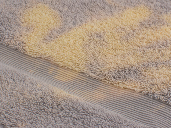 Pale bleach marks on a gray towel where the color has changed