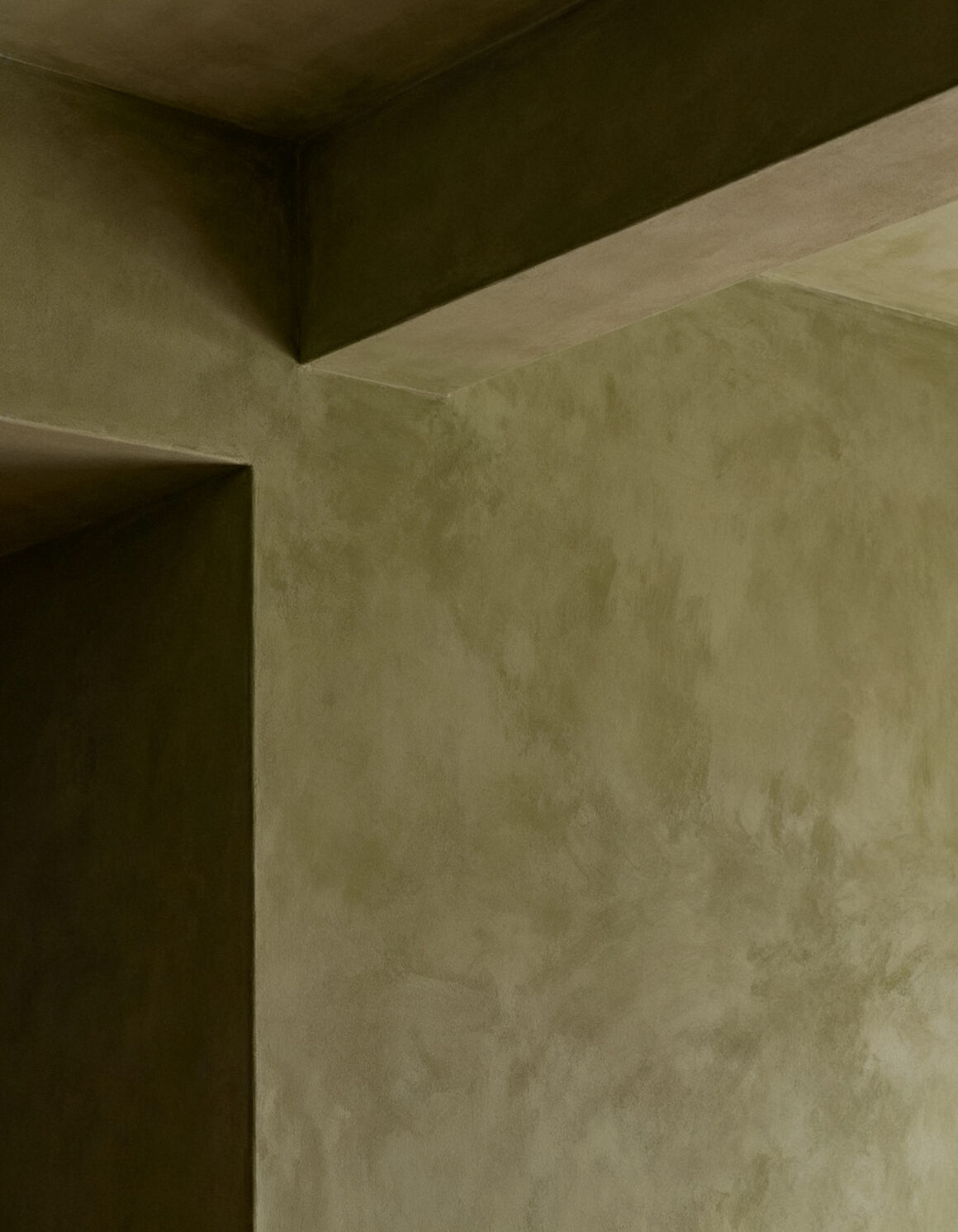 Olive green walls meeting at a corner in an empty room