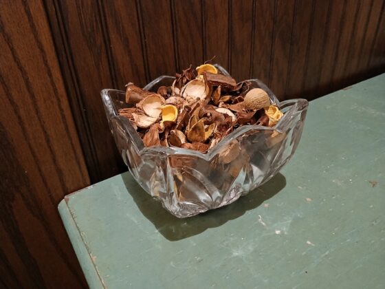 A cut glass bowl of faded potpourri on a painted surface
