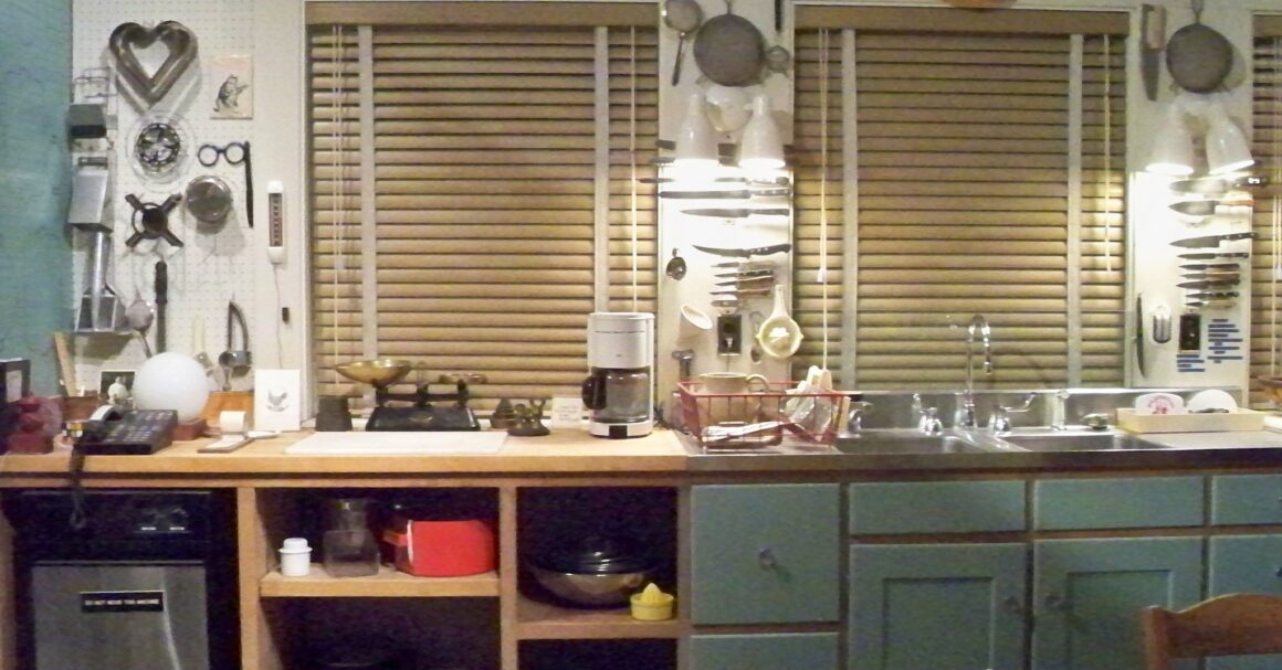 Julia Child's kitchen at the Smithsonian, with a long wooden counter, a pegboard of cooking tools and knives, and blue-green cabinets below