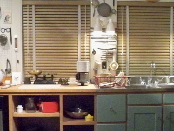 Julia Child's kitchen at the Smithsonian, with a long wooden counter, a pegboard of cooking tools and knives, and blue-green cabinets below