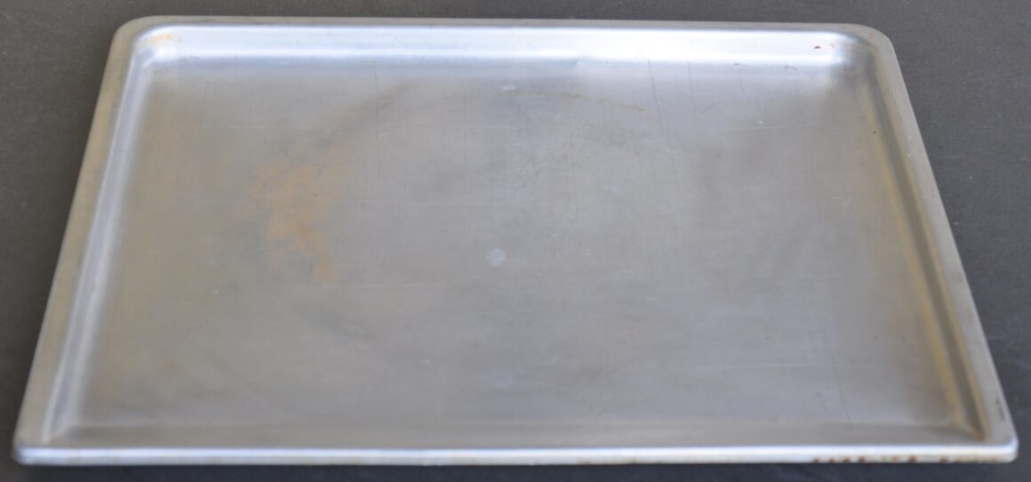 An old metal baking sheet with scratches and discoloration from years of use.