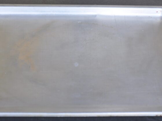 An old metal baking sheet with scratches and discoloration from years of use.
