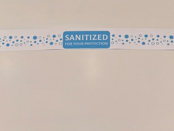 A sanitary band reading "Sanitized for your protection" across a closed white toilet lid